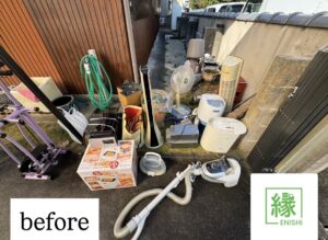 名古屋市緑区の住宅脇に置かれた扇風機・除湿機・掃除機・キッチン家電・ラックなど多数の不用品が積まれている様子